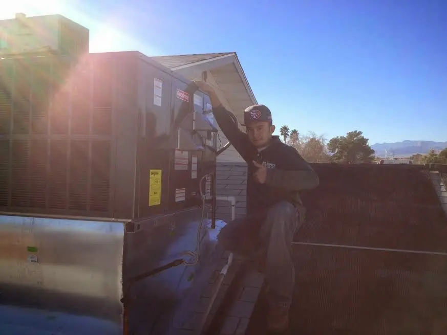 HVAC technician performing Air Duct Cleaning on a rooftop unit in Highland